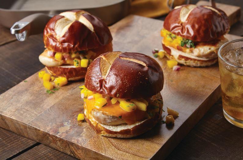 Mango salsa grilled chicken sandwiches on a wood serving board