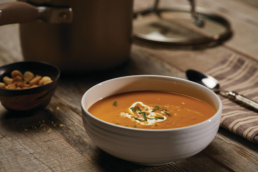 Pumpkin soup in a white bowl on wood table