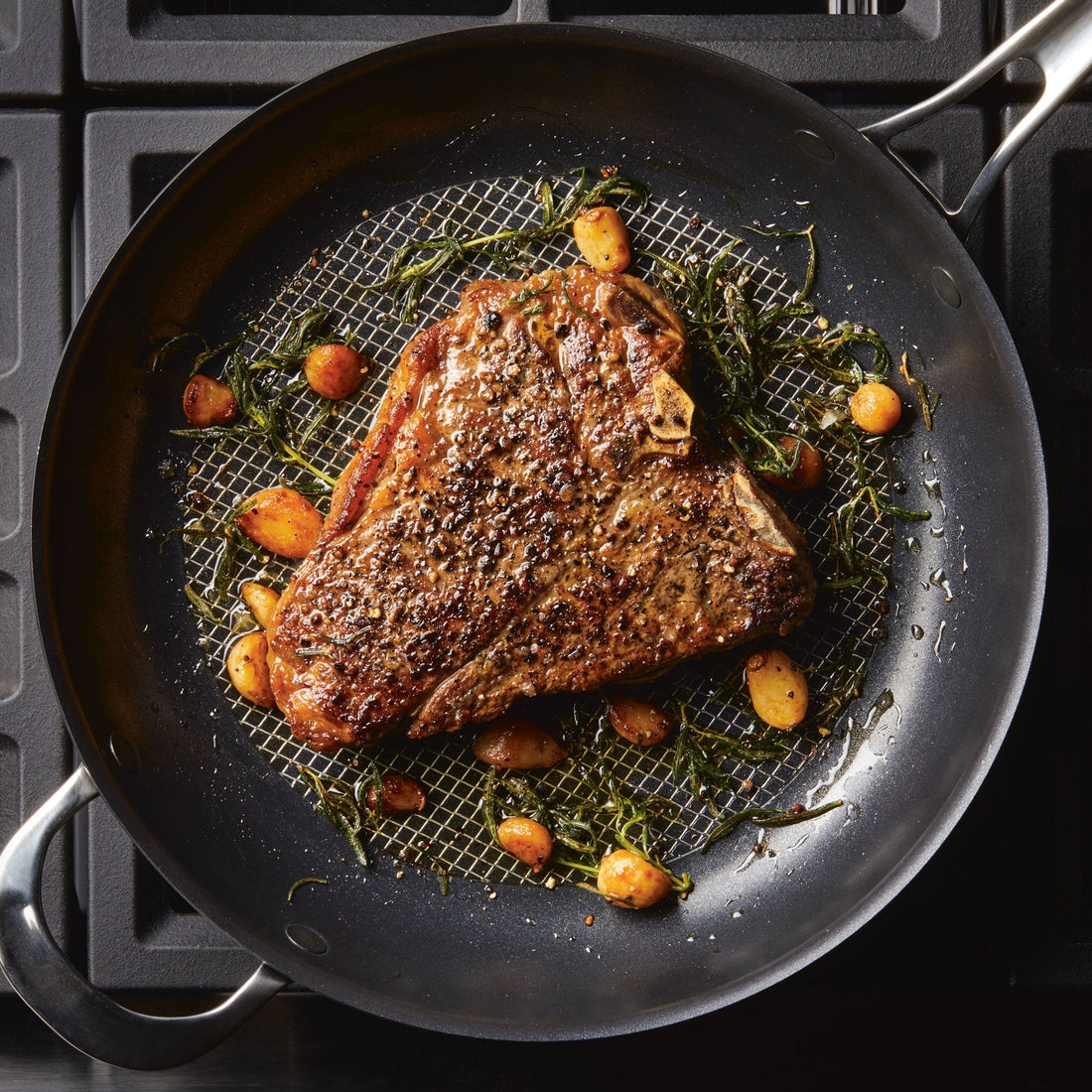 Steak searing with garlic and aromatics on an Anolon X nonstick frying pan. 