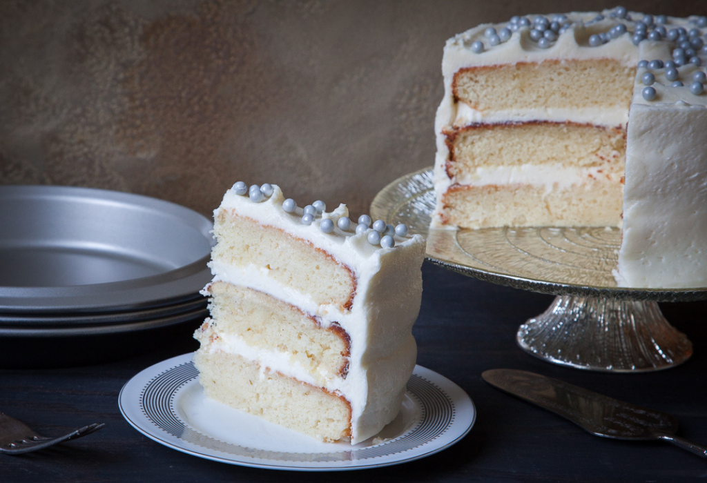 Champagne cake on a cake stand with a cut out slice on a plate