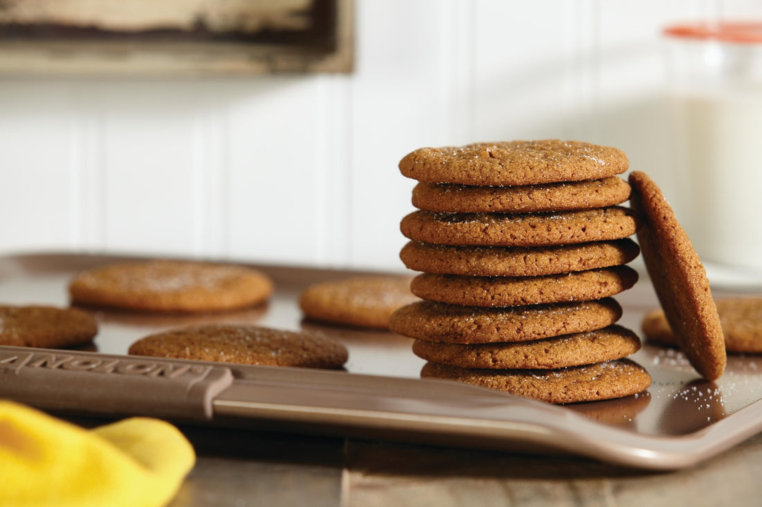 Ginger molasses cookies stacked on an Anolon baking sheet