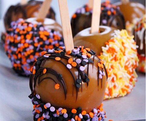 Halloween decorated caramel apples on a baking sheet