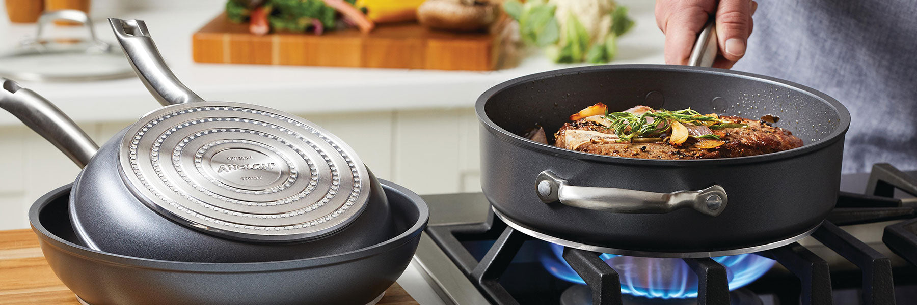 A person cooks a seasoned steak with vegetables in a deep nonstick pan on a gas stove; two other stacked pans are nearby on the kitchen counter.