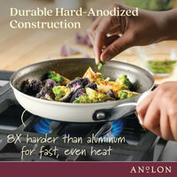 A person sprinkles seasoning onto roasted vegetables in a frying pan on a stove. The text reads, Durable Hard-Anodized Construction and 8X harder than aluminum for fast, even heat. The pan handle has the brand name Anolon.