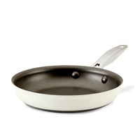 A non-stick frying pan with a white exterior and a dark interior, featuring a silver handle, is shown against a plain white background.