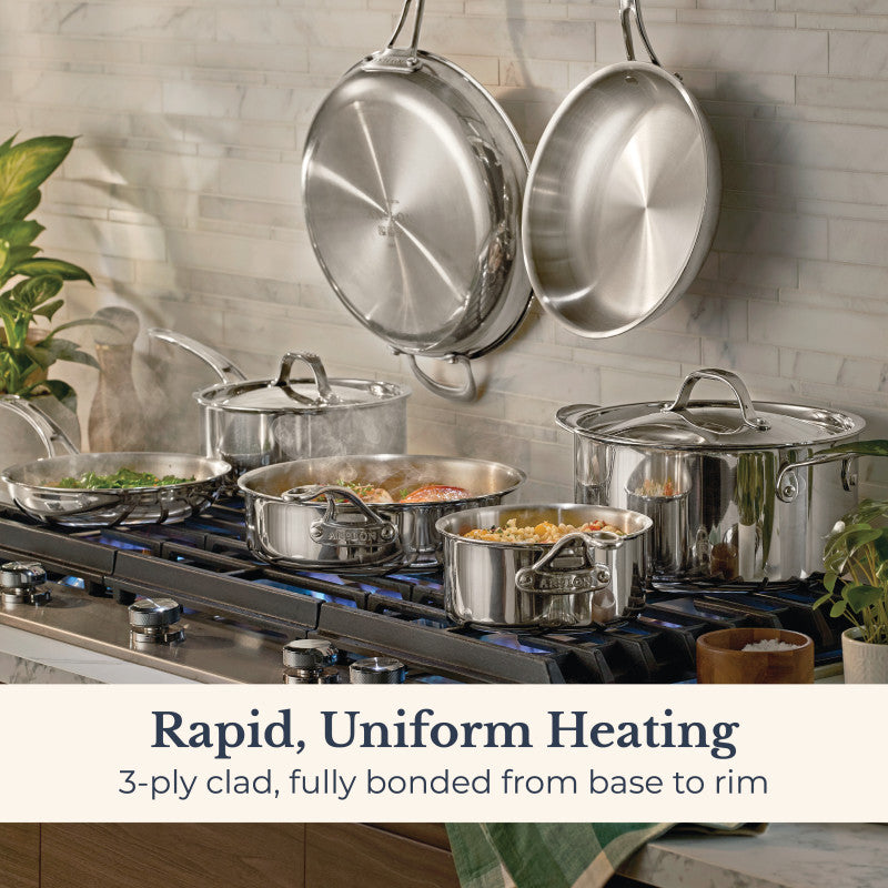 A modern kitchen features the EverLast Tri-Ply Clad Stainless Steel 11-Piece Cookware Set on a gas stove with two pans hanging above. Text: Rapid, Uniform Heating. 3-ply clad construction bonded from base to rim.