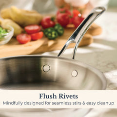 A close-up of the EverLast Tri-Ply Clad Stainless Steel 10-Piece Cookware Set featuring flush rivets on a kitchen counter, with sliced vegetables in the background. Text: Flush Rivets. Designed for seamless stirs & easy cleanup.