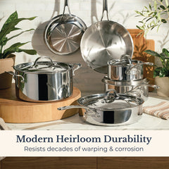 An EverLast Tri-Ply Clad Stainless Steel 10-Piece Cookware Set gleams on a kitchen counter and hangs on the wall amid green plants. Text: Modern Heirloom Durability—resists decades of warping & corrosion.