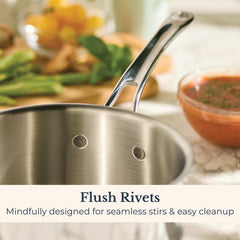 A close-up of the EverLast Tri-Ply Clad Stainless Steel 3-Quart Saucepan with Lid, featuring interior flush rivets, sits on a marble counter near tomato sauce and fresh vegetables. Text: “Flush Rivets. Designed for seamless stirs & easy cleanup.”.