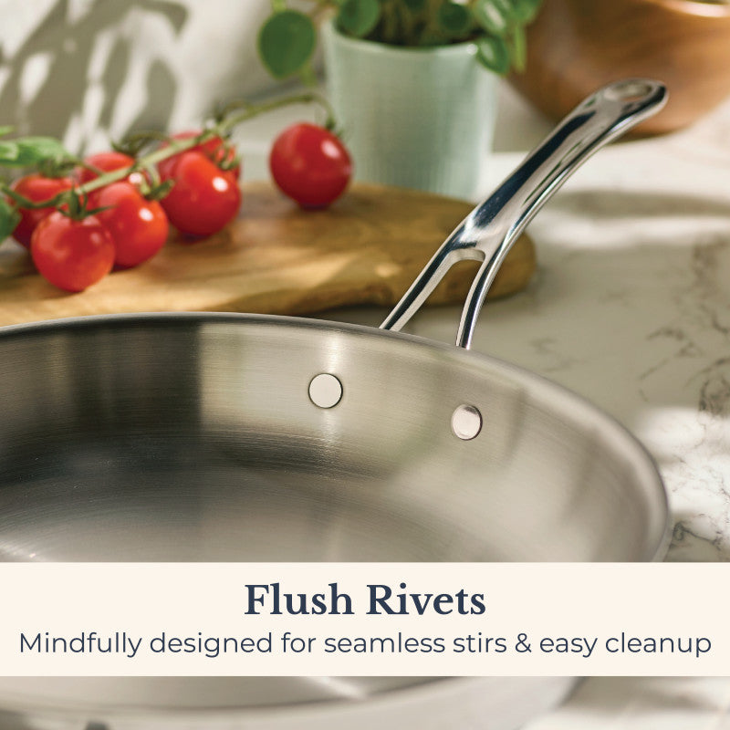An EverLast Tri-Ply Clad Stainless Steel 12.5-Inch Frying Pan with Lid and Helper Handle sits on the counter, featuring flush rivets for seamless stirring and easy cleanup—ideal for home chefs.