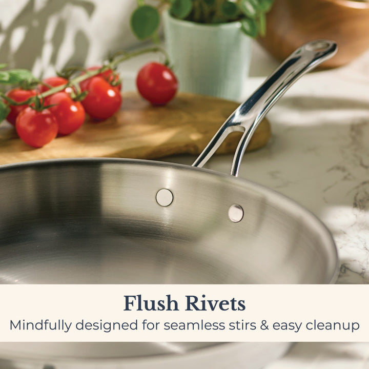 An EverLast Tri-Ply Clad Stainless Steel 12.5-Inch Frying Pan with Lid and Helper Handle sits on the counter, featuring flush rivets for seamless stirring and easy cleanup—ideal for home chefs.