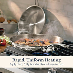 A stainless steel frying pan from the EverLast Tri-Ply Clad Stainless Steel Frying Pan Set cooks food on a stovetop, steam rising. The lid stands upright behind it. Text: Rapid, Uniform Heating. Fully bonded tri-ply construction from base to rim.