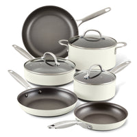 A set of white ceramic cookware with metal handles, including two frying pans, two saucepans with lids, a sauté pan with a lid, and a stockpot with a lid, arranged on a white background.
