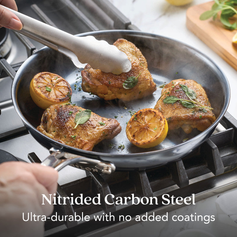 A person cooks seasoned chicken thighs and lemons in the 10-Inch N₂ Carbon Steel Frying Pan by N₂ Carbon Steel. Ultra-durable, rust resistant, and develops a natural nonstick patina with use.