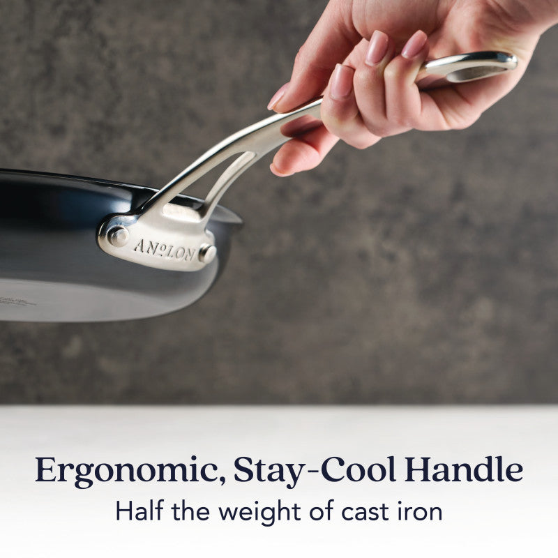 A hand holds the 10-Inch N₂ Carbon Steel Frying Pan by N₂ Carbon Steel, featuring a black carbon steel body and silver ergonomic, stay-cool handle. Rust resistant and half the weight of cast iron.