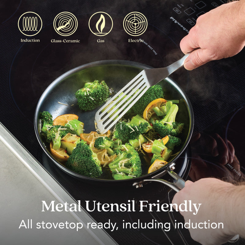 A person uses a metal spatula to cook veggies in the 10-Inch N₂ Carbon Steel Frying Pan by N₂ Carbon Steel on an induction cooktop. Metal utensil friendly, rust resistant, nonstick patina. Works on all stovetops, including induction.