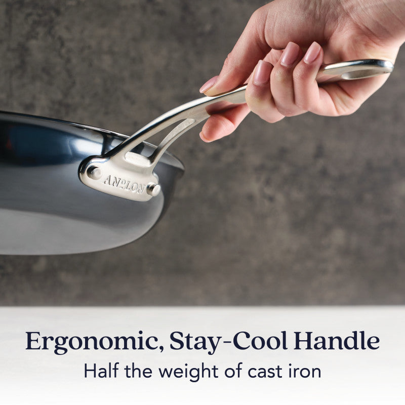 A hand grips the N₂ Carbon Steel 12-Inch Frying Pan’s ergonomic, stay-cool metal handle. Text: Ergonomic, Stay-Cool Handle. Naturally evolving nonstick surface. Half the weight of cast iron.
