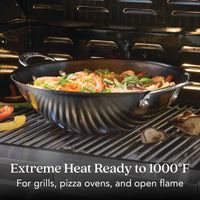 The N2 Carbon Steel Wok by N2 Carbon Steel is shown on a grill, filled with stir-fried veggies and shrimp. Text reads: “Extreme Heat Ready to 1000°F. For grills, pizza ovens, and open flame.”.