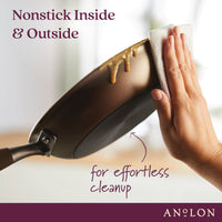 A hand wipes a nonstick frying pan with a paper towel. The pan has a mess on the exterior but is easily cleaned. Text: Nonstick Inside & Outside for effortless cleanup. The image promotes ANOLON cookware.