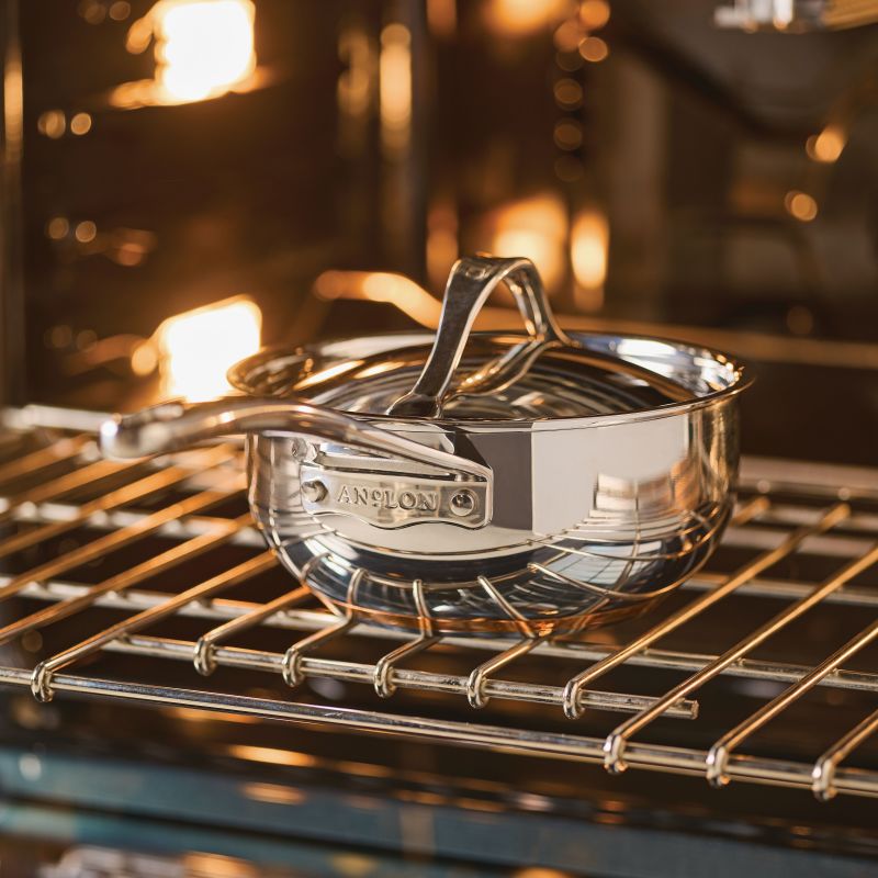 A Nouvelle Stainless 2.5-Quart Saucier with Lid rests on an oven rack, reflecting warm light and delivering excellent heat control.