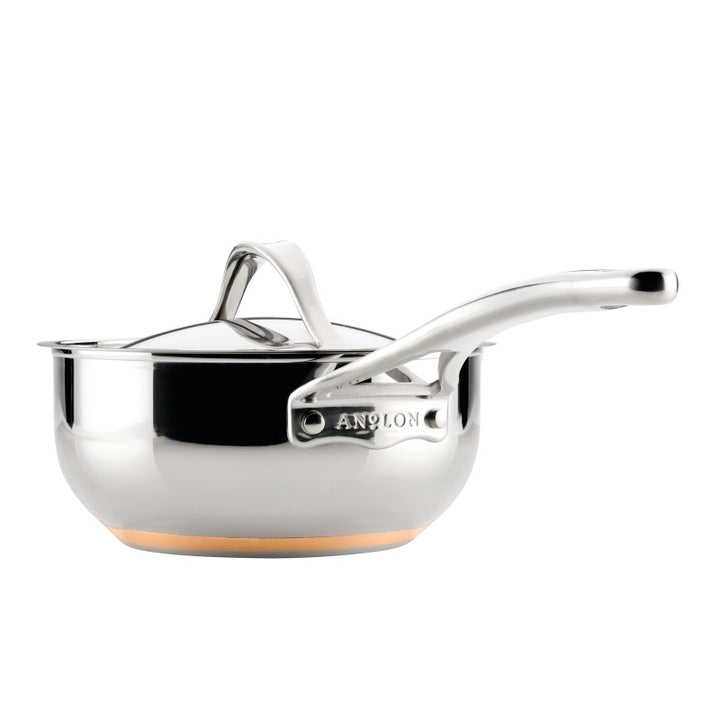 The Nouvelle Stainless 2.5-Quart Saucier with Lid features a long handle, matching lid, shiny finish, and thick copper base for even heat distribution—reflecting Anolon-inspired craftsmanship.