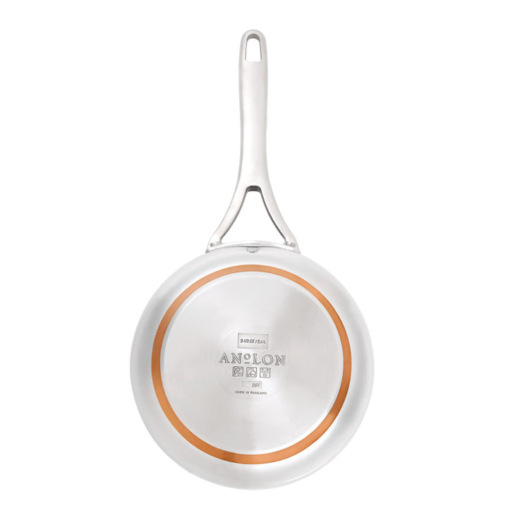 A 2.5-Quart Saucier with Lid from the Nouvelle Stainless line is shown from the bottom, featuring a silver handle, circular copper ring for heat control, and engravings of the brand name and product details in the center.