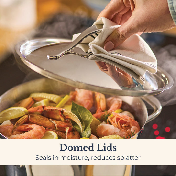 A hand lifts the lid with a cloth from a steaming Nouvelle Stainless 6.5-Quart Stockpot filled with shrimp, lemon slices, and herbs. Domed lid seals in moisture and reduces splatter—essential for flavorful cooking results.