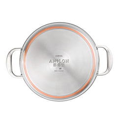Top view of a Nouvelle Stainless 6.5-Quart Stockpot with lid, featuring two handles and a copper ring near the base. The cookware bottom is stamped with the brand name and symbols.