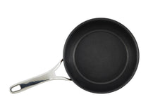 A non-stick frying pan with a silver handle is placed against a plain white background. The pan is positioned to the right, showcasing its circular shape and smooth black surface.