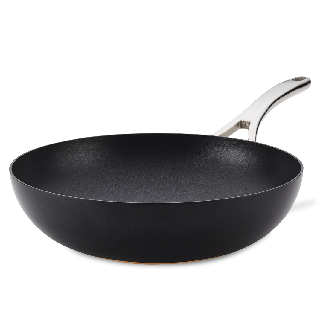 The Nouvelle Copper Luxe 12-Inch Stir Fry pan features a nonstick black surface, wide base, silver metal handle, and is induction suitable, shown on a plain white background.
