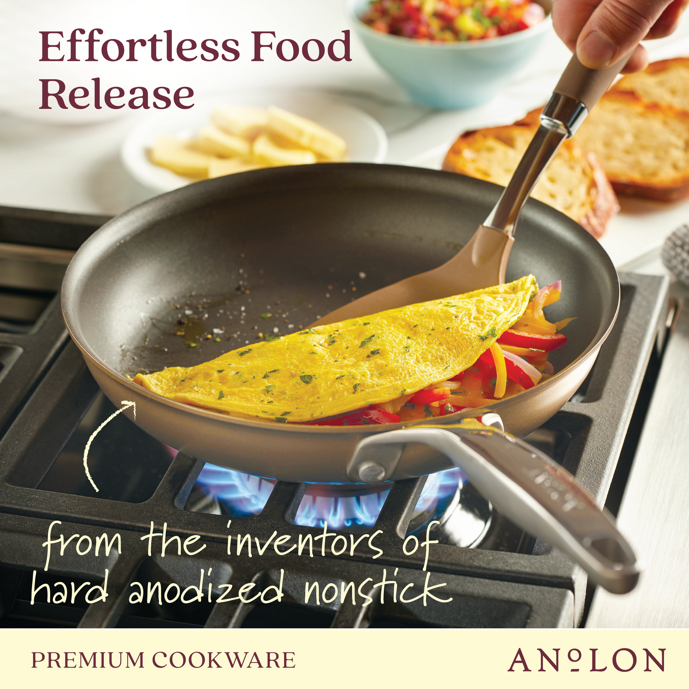 A pan on a stove holds an omelet with sliced vegetables. A spatula lifts the omelet, showing the nonstick surface. The text reads, Effortless Food Release and from the inventors of hard anodized nonstick, with Anolon branding.