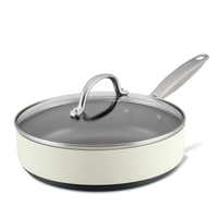 A cream-colored non-stick frying pan with a long handle and a transparent glass lid. The pan is set against a white background, showcasing its smooth surface and modern design.
