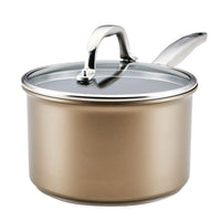 A gold-colored saucepan with a glass lid and a metal handle. The pot has a smooth, shiny surface, and the lid is adorned with a metallic knob for easy handling. The handle is ergonomically designed, attached to the pots side.