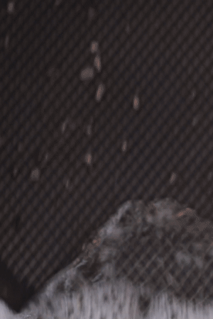 A close-up, looping GIF demonstrating how to clean Anolon X cookware. A person uses a soft soapy sponge to gently scrub the interior of the pan, showing how easily food residue releases from the SearTech™ stainless steel mesh and nonstick hybrid surface.