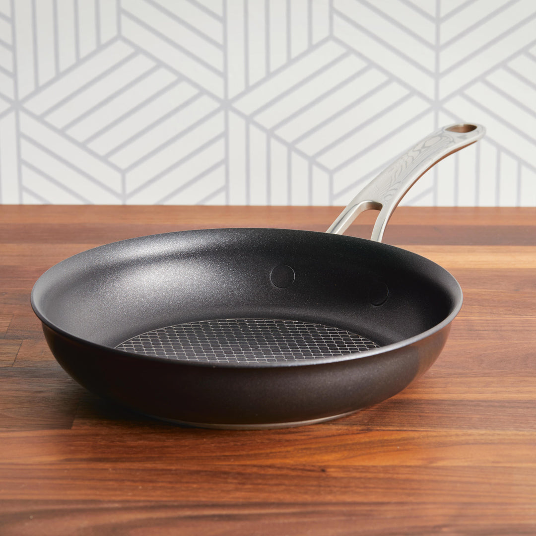 A black frying pan with a metal handle on a wooden kitchen counter.