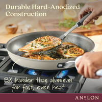 A person is cooking seasoned chicken breasts and orange slices in a nonstick frying pan on a stove. The pan is advertised as durable, hard-anodized, and 8 times harder than aluminum for fast, even heat. Brand name Anolon is shown.