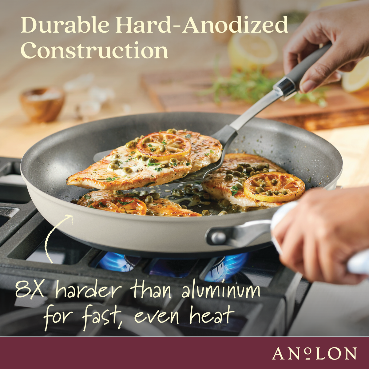 A person is cooking seasoned chicken breasts and orange slices in a nonstick frying pan on a stove. The pan is advertised as durable, hard-anodized, and 8 times harder than aluminum for fast, even heat. Brand name Anolon is shown.