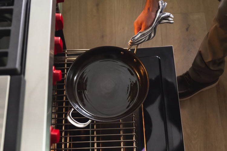 Cleaned and oiled carbon steel pan being put into an oven