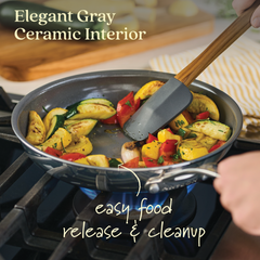 A hand stirs squash, zucchini, and red peppers in an EverLast Ceramic Stainless Steel frying pan featuring an elegant gray ceramic nonstick interior on the stove, ensuring easy food release and cleanup.