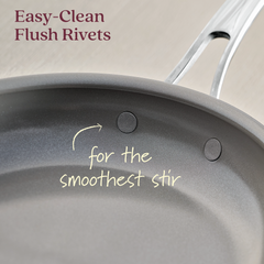 Close-up of an EverLast Ceramic Stainless Steel pan, highlighting its interior. The text reads, Easy-Clean Flush Rivets for the smoothest stir, focusing on the ease of cleaning and cooking with flush rivets in this 3-Piece Ceramic Nonstick Stainless Steel Frying Pan Set.