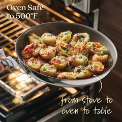 Showcasing the EverLast Ceramic Stainless Steel 3-Piece Nonstick Frying Pan Set, a person holds a pan of stuffed pasta shells with herbs and cheese in front of an open oven. Text reads Oven Safe to 500°F and from stove to oven to table, with the pan resting on a kitchen towel.