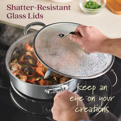 Lifting a shatter-resistant glass lid from an 11-Piece EverLast Ceramic Nonstick Stainless Steel Cookware Set pan filled with shrimp and mussels, the text highlights Ceramic Nonstick Coating for easy cleanup and Shatter-Resistant Glass Lids to monitor your creations.