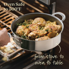 A person holds an EverLast Ceramic Stainless Steel pan with chicken and rice, garnished with herbs and lemon slices, by an oven. Text reads, Oven Safe to 500°F and from stove to oven to table. Featuring the 11-Piece Ceramic Nonstick Stainless Steel Cookware Set.