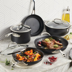 A kitchen scene showcases the AnolonX 8-Piece Hybrid Nonstick Cookware Set, featuring induction-suitable cookware with metal handles, including a frying pan, saucepans, and a sauté pan on a marble countertop. Visible ingredients include a cooked meat dish, roasted vegetables, herbs, and a bottle of oil—perfectly prepared using SearTech technology.