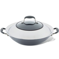A covered wok with black handles and a lid sits on a white background. The wok has a metallic finish.