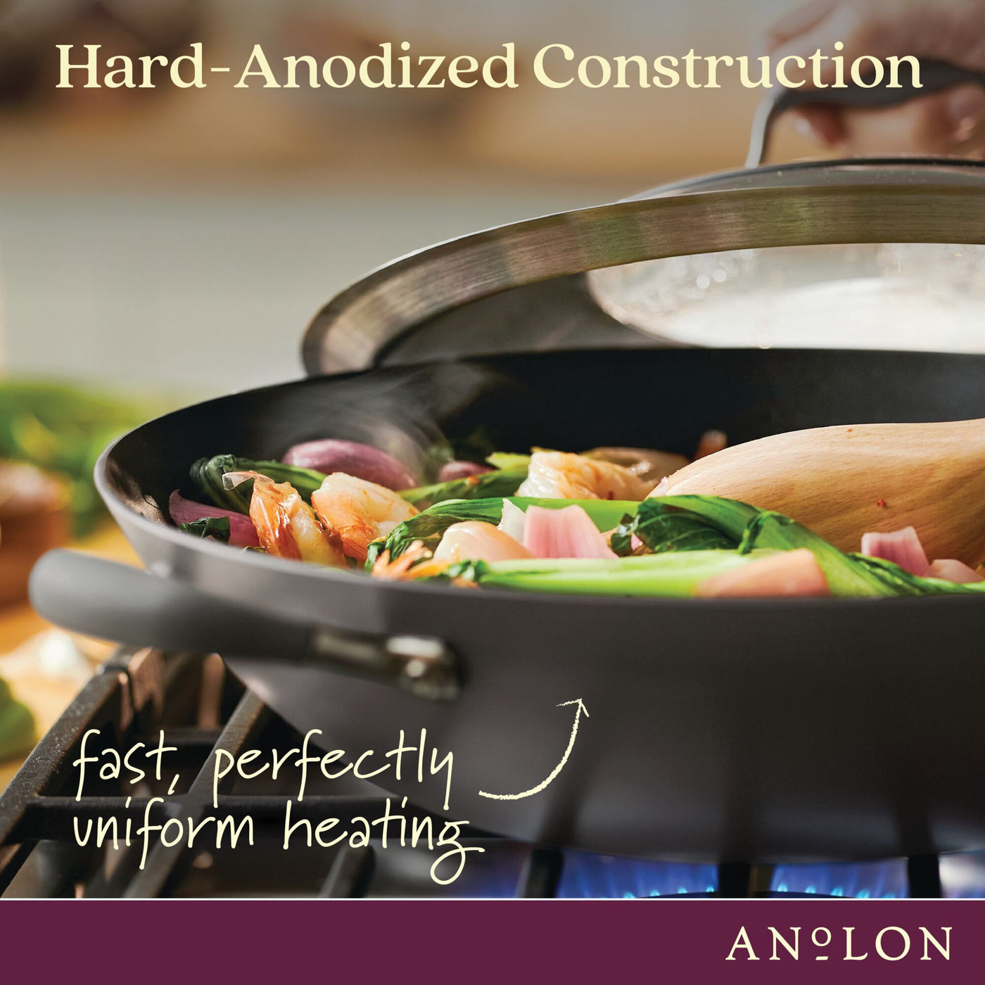 A close-up of vegetables being sautéed in a hard-anodized frying pan. A wooden spatula is seen stirring the contents. Text reads, Hard-Anodized Construction - fast, perfectly uniform heating. ANOLON logo at the bottom.