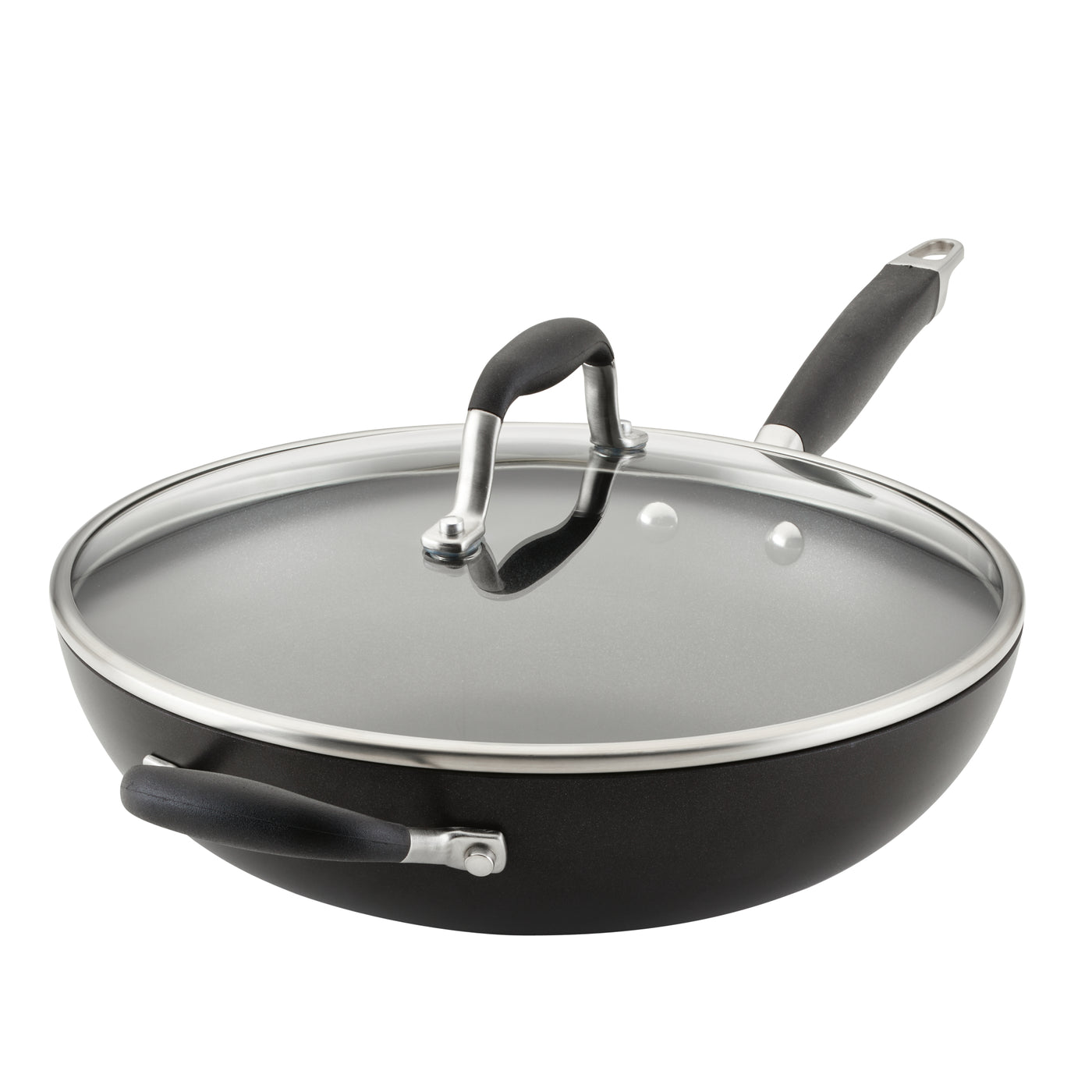 A black non-stick deep sauté pan with a glass lid and stainless steel rims sits against a white background. The pan has two black handles, one long and one short, and a steam vent on the lid.