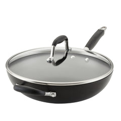 The 12-Inch Hard Anodized Nonstick Deep Frying Pan with Lid by Advanced Home features a sleek black finish and modern design, including a long handle and tempered glass lid with a stainless steel rim and black knob. This pan also includes a helper handle for easy lifting, making it ideal for various cooking tasks.