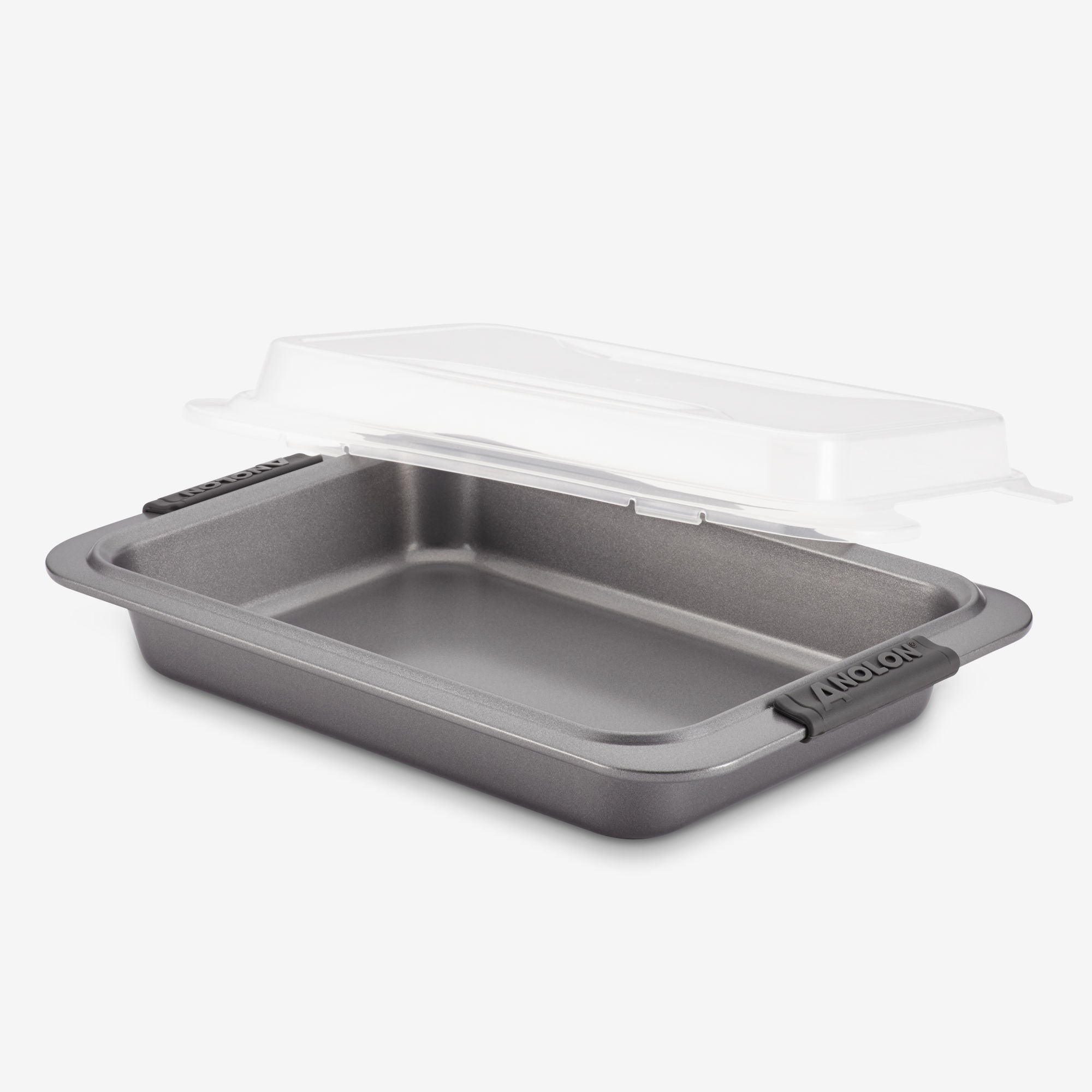 A rectangular non-stick baking pan with handles, featuring a transparent plastic lid slightly lifted above it. The lid is designed to securely cover the pan, providing convenience for storage or transport.
