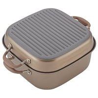 A square, bronze-colored pan with a grill lid, featuring two light brown handles. The lid has a ridged surface, suggesting its designed for grilling. The pan appears sturdy and portable, ideal for kitchen use.